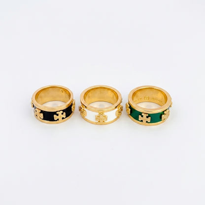 Three gold rings with interlocking cross motifs and colored enamel bands, displayed side by side on a light gray background.