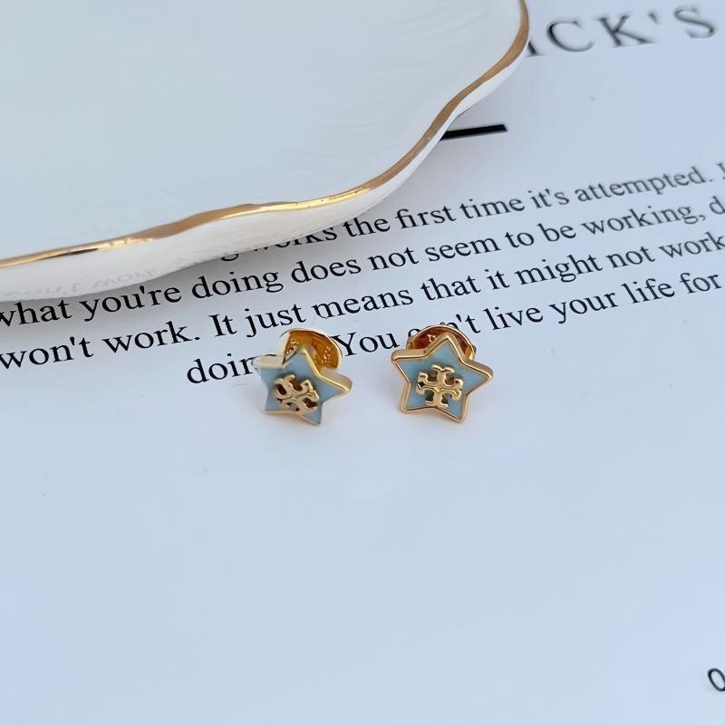 Clean shot of a single earring against a dark blue or midnight-inspired background, making the star charm and its sparkle stand out like a star in the night sky.