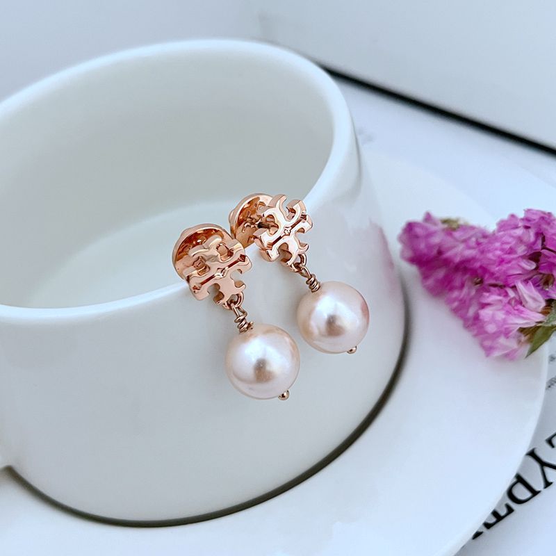  Clean, vertical shot of a single earring against a soft, neutral background, showcasing the pearl drop and its gold-tone setting.