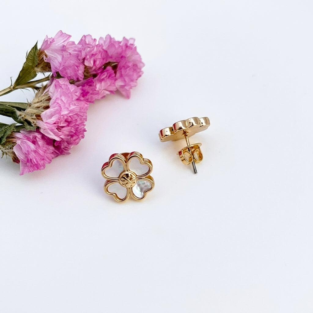 Gold floral earrings with pink flowers on a white background