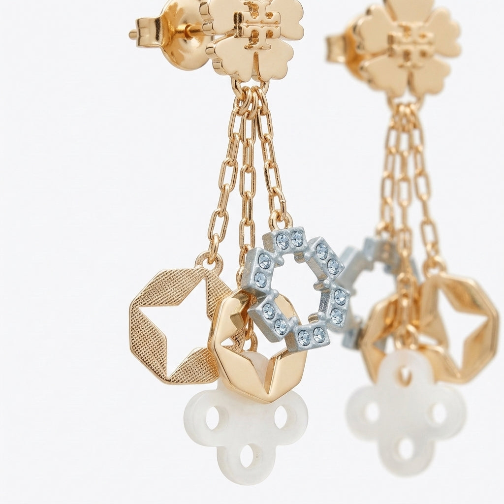 Gold dangle earrings with floral studs, chain links, textured geometric charms, a light blue rhinestone-accented ring, and white flower-shaped drops, shown on a clean white background.