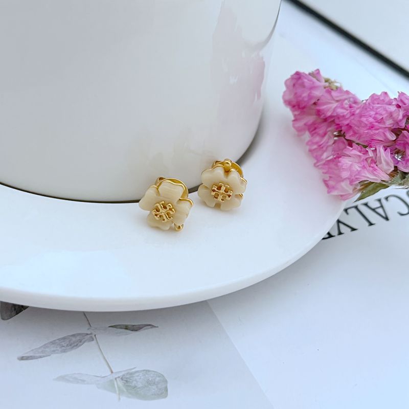 Both studs displayed face-up on a soft, light background (white or pale blue), highlighting the delicate blue enamel petals.