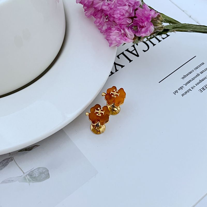Both studs displayed face-up on a soft, light background (white or pale blue), highlighting the delicate blue enamel petals.
