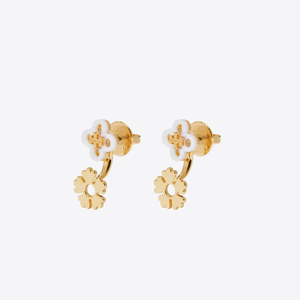A pair of gold and white flower-shaped stud earrings on a light gray background.