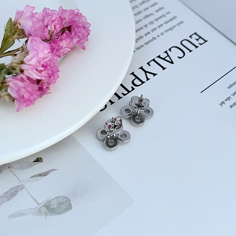 Extreme close-up of one stud, focusing on the pave crystal petals and the metal outlines of the flower.