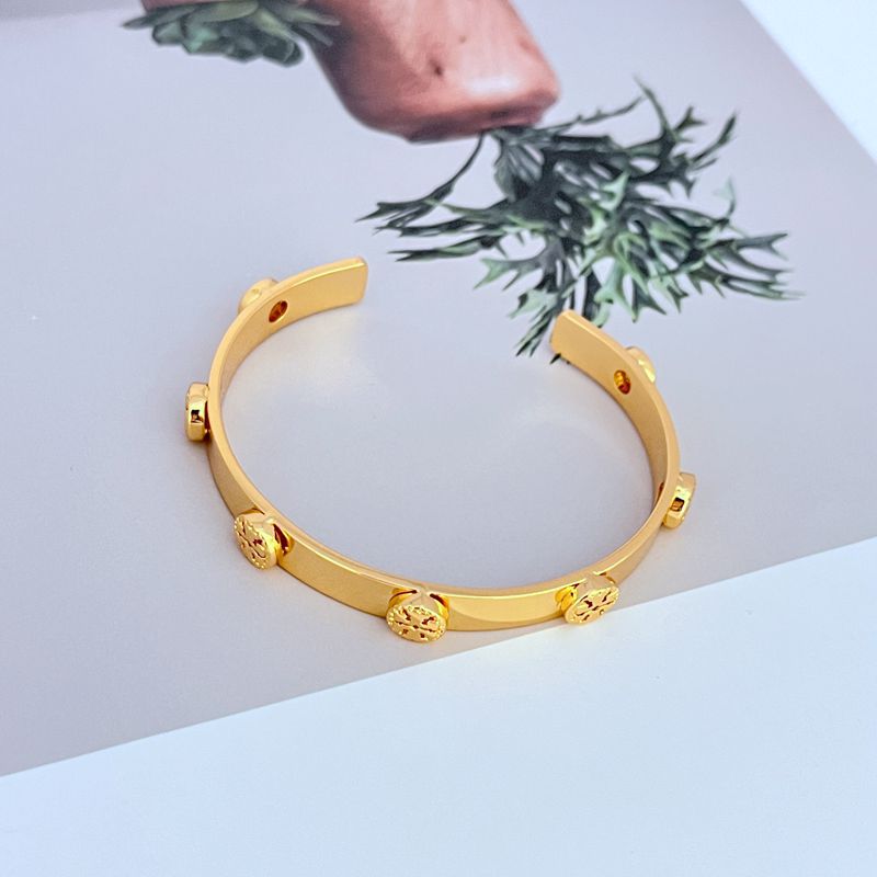 Ring displayed upright or at an angle on a solid background, highlighting its wide cuff shape and prominent logo.