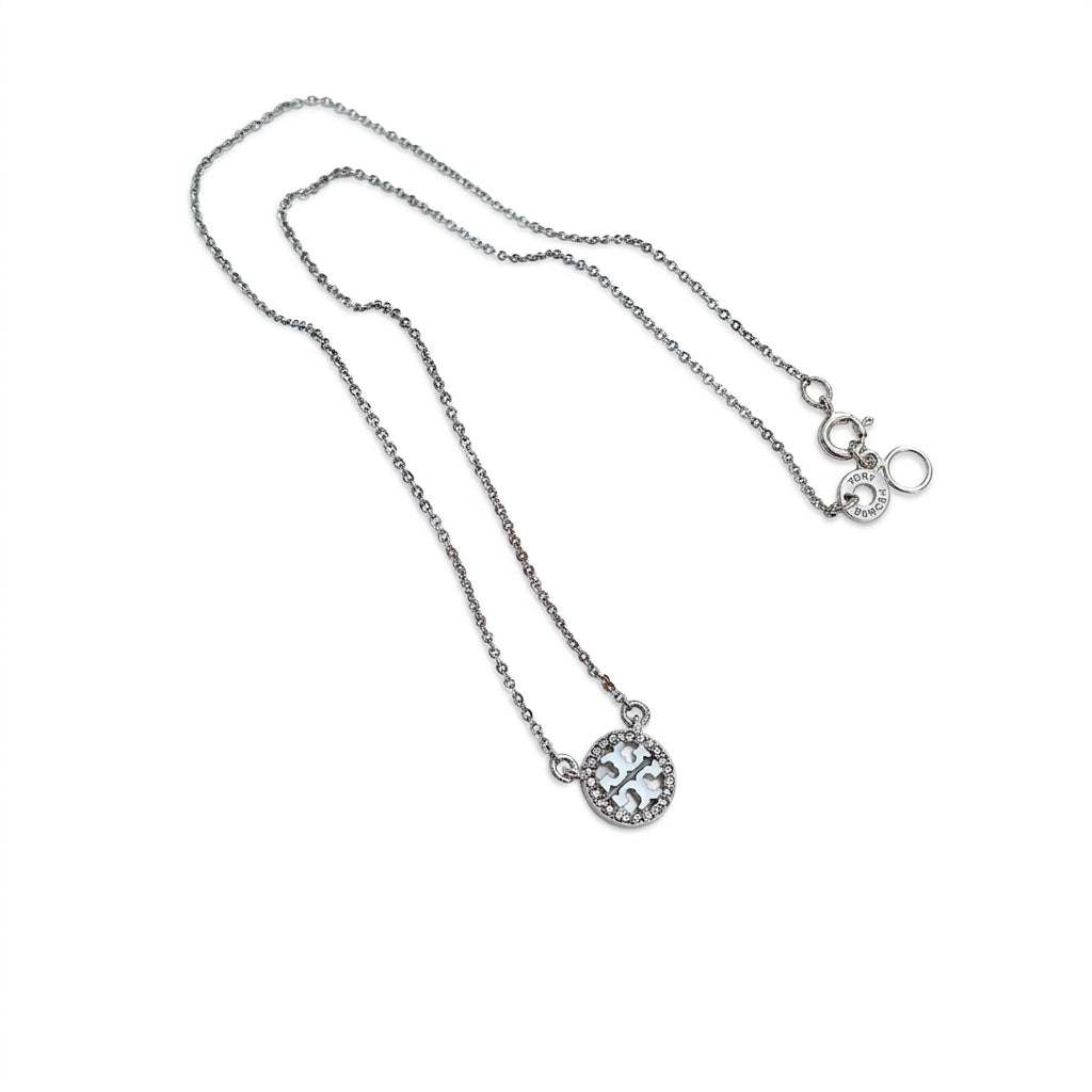 A silver-toned chain necklace with a small oval pendant set with clear stones, displayed on a plain white background.