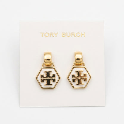 A pair of gold-tone hexagonal dangle earrings with a white enamel center and a black Tory Burch cross logo, displayed on a white backing card printed with the brand name.