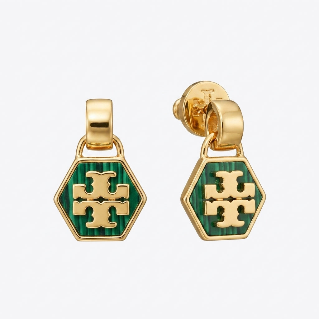 A pair of gold-tone dangle earrings with hexagonal green enamel charms featuring the Tory Burch cross logo, shown on a light gray background.