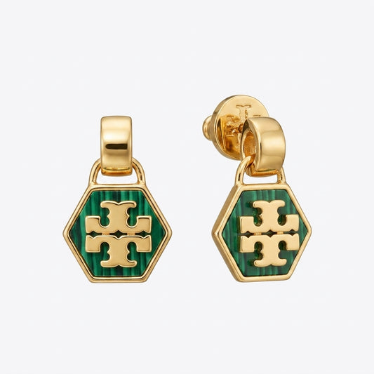 A pair of gold-tone dangle earrings with hexagonal green enamel charms featuring the Tory Burch cross logo, shown on a light gray background.