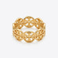 A gold-tone filigree bangle bracelet with a repeating interlocking monogram pattern, shown on a light gray background.