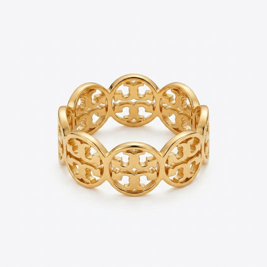 A gold-tone filigree bangle bracelet with a repeating interlocking monogram pattern, shown on a light gray background.