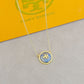 Necklace with a round pendant on a gray surface with a Tory Burch box in the background.