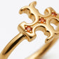 Gold ring with a stylized openwork cross or crown-like top set with small round orange gemstones, photographed close up on a white background.