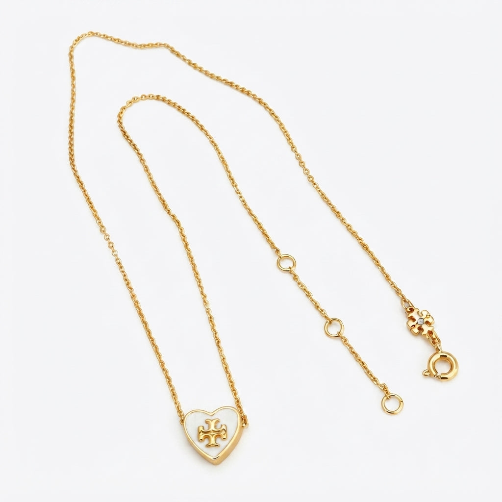A delicate gold chain necklace featuring a small heart-shaped pendant with a cross motif, displayed on a clean white background.
