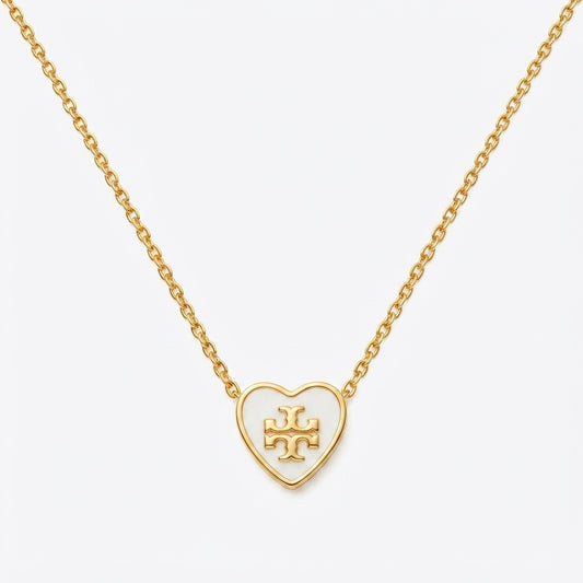 A gold heart-shaped pendant necklace with an open heart design and a central monogram logo, suspended from a delicate gold chain against a light gray background.