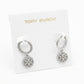 A pair of silver-tone Tory Burch hoop earrings with circular logo charms, displayed on a white branded card.