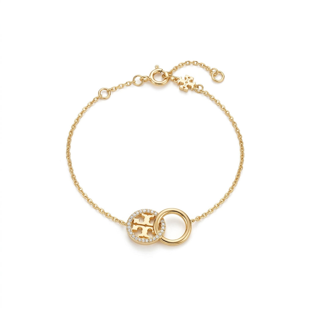 A delicate gold chain bracelet featuring a circular medallion with a pavé-set 'H' and a polished gold ring, displayed on a clean white background.