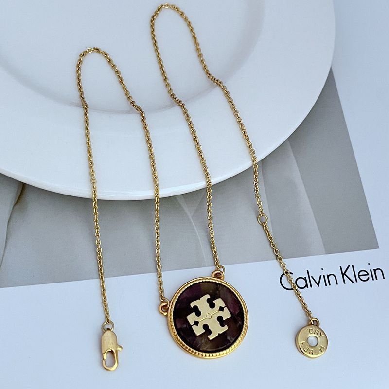 Gold necklace with a purple pendant on a white surface