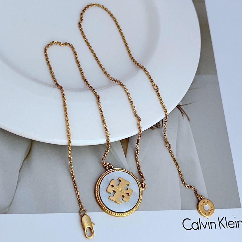 Gold necklace with a pendant on a white surface, Calvin Klein brand visible