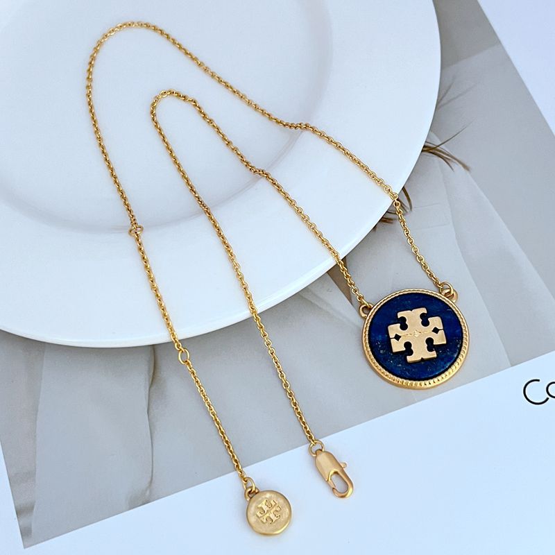 Gold necklace with a blue pendant on a white surface