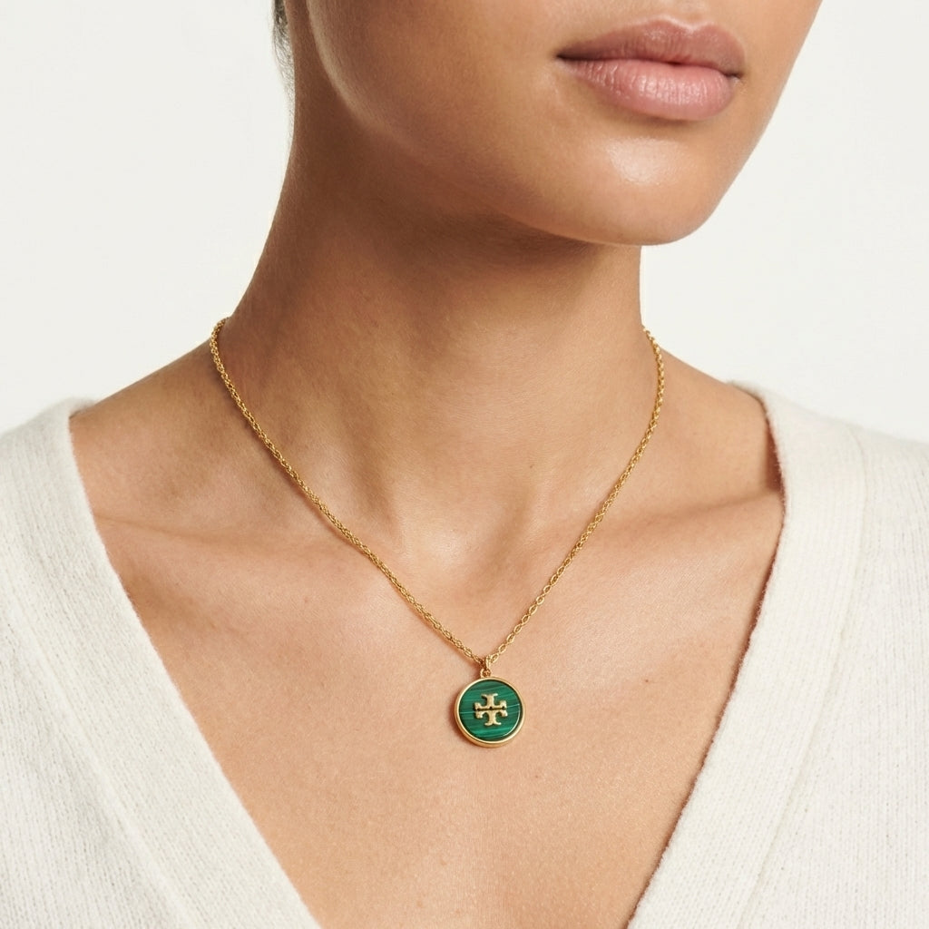 Close-up from lips to chest, cropped above the mouth. Model in a white top, wearing a single necklace.