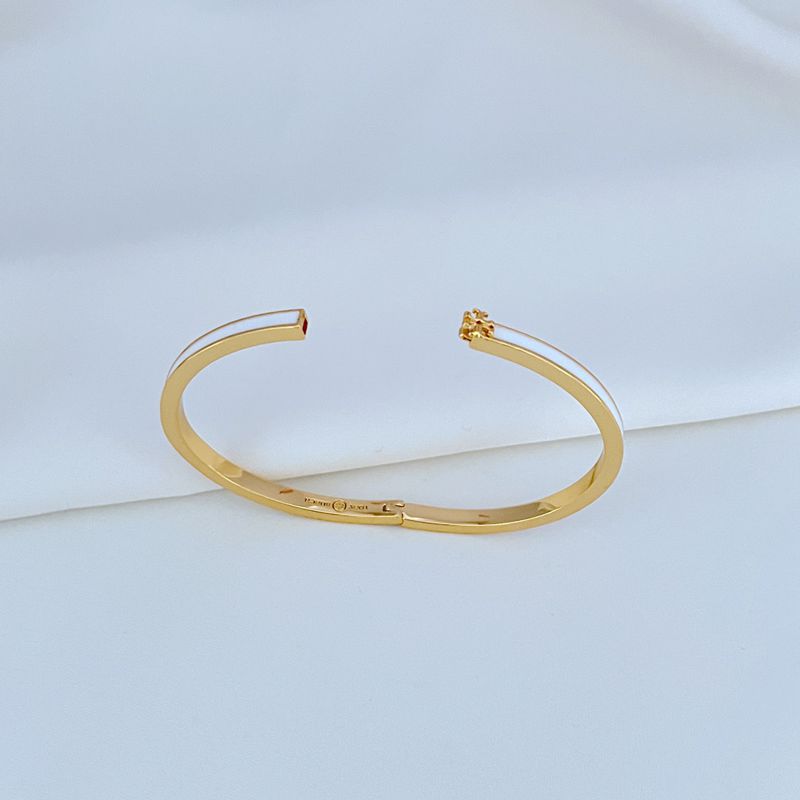 Close-up focused on the Double T logo, showcasing the smooth enamel fill and polished metal edges.