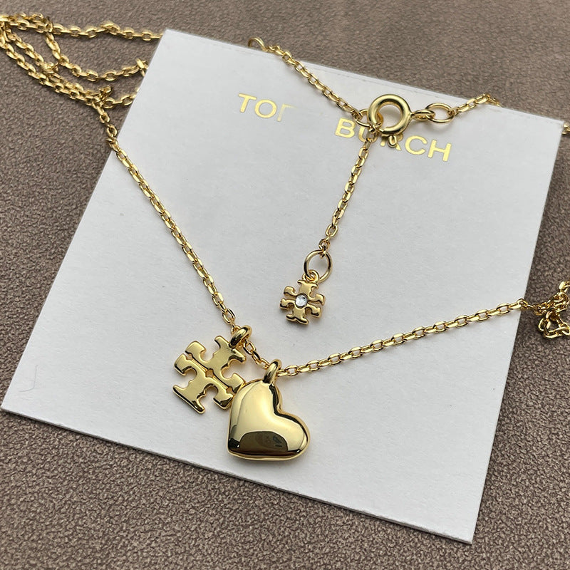 Close-up focused on the charm cluster, highlighting each element: crystal sparkle, heart shape, pearl luster, and engraved T logo.