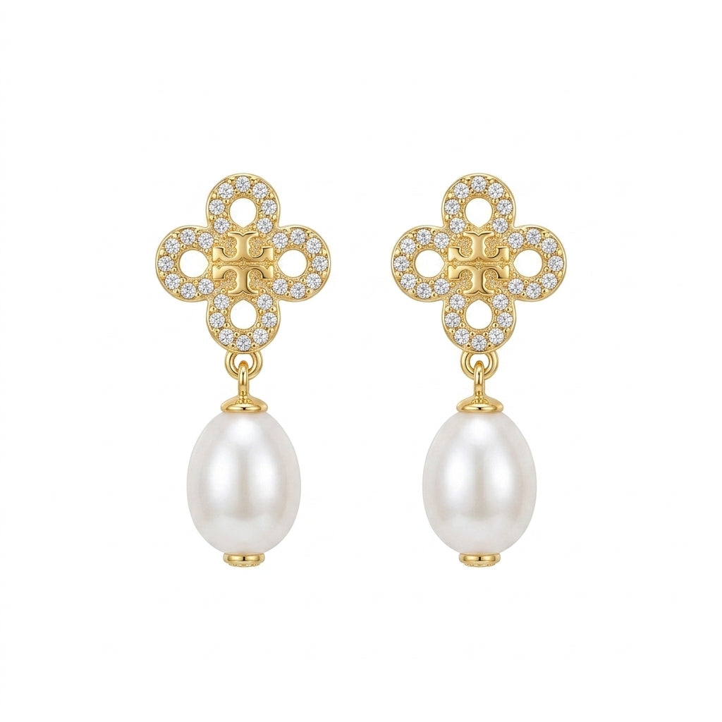 A pair of gold and pearl drop earrings featuring a clover-shaped top set with small clear crystals and a dangling white pearl below, shown on a plain white background.