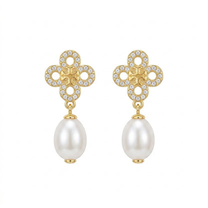 A pair of gold and pearl drop earrings featuring a clover-shaped top set with small clear crystals and a dangling white pearl below, shown on a plain white background.