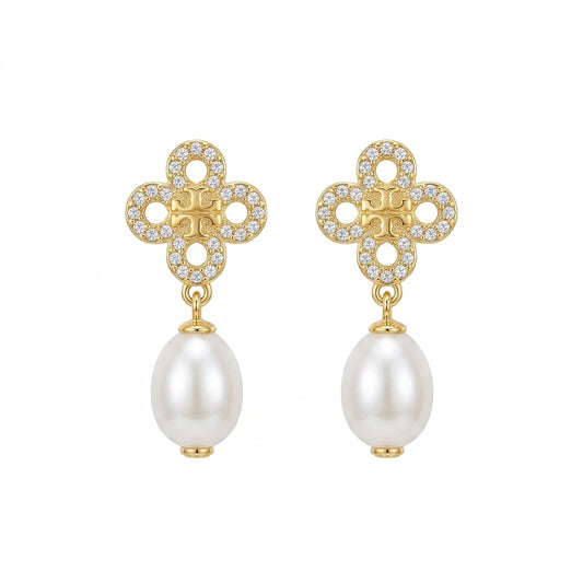 A pair of gold and pearl drop earrings featuring a clover-shaped top set with small clear crystals and a dangling white pearl below, shown on a plain white background.
