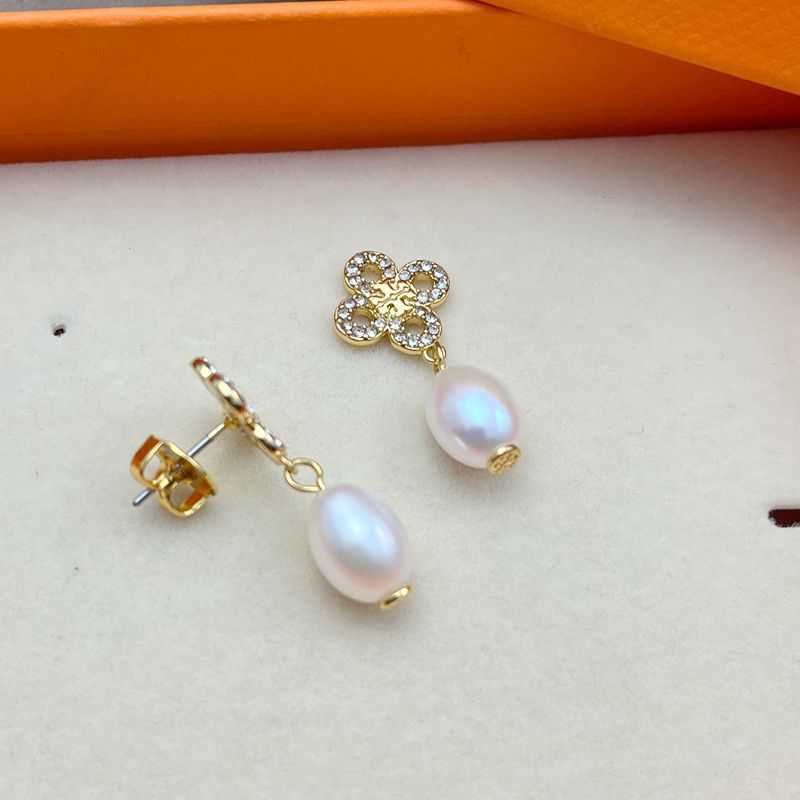 Both earrings displayed hanging freely against a light, soft-focus background, showing the clover charm above the pearl drop.