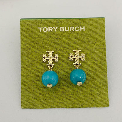 Tory Burch earrings with turquoise beads and gold accents on a green card.