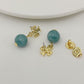 Gold earrings with turquoise beads on a white surface