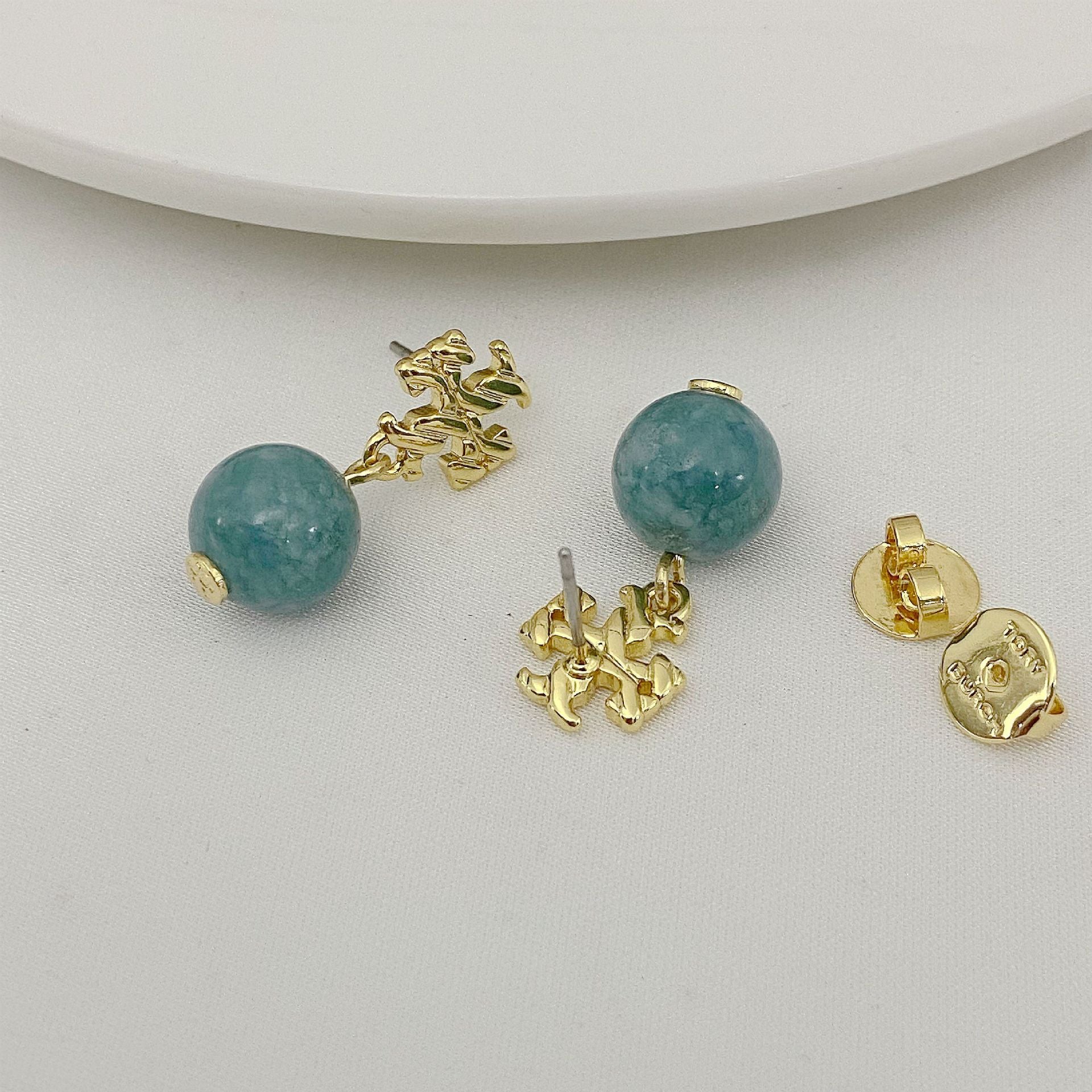 Gold earrings with turquoise beads on a white surface