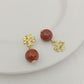 Pair of earrings with red beads and gold accents on a white plate.