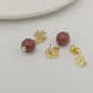 Gold earrings with red gemstones on a light gray background