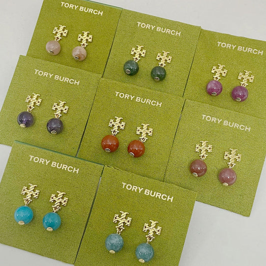 Tory Burch earrings on green cards with various colored beads.