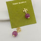 Gold earrings with pink beads on a Tory Burch branded card.
