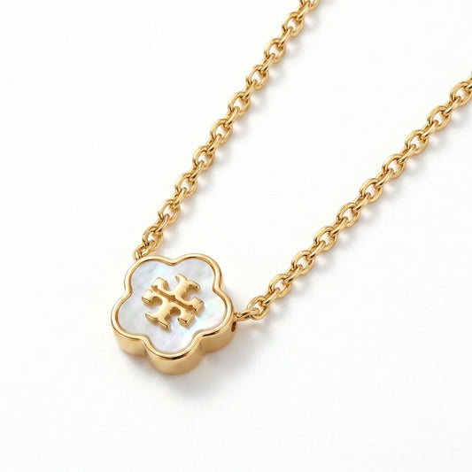 A gold chain necklace featuring a clover-shaped pendant with a white mother-of-pearl inlay and a gold monogram logo in the center, shown on a clean white background.