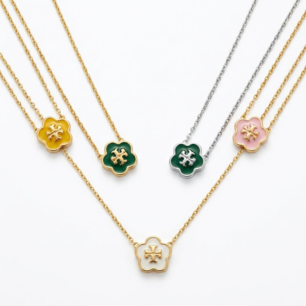 Five floral clover pendant necklaces on layered chains, shown on a clean white background. The necklaces feature gold, silver, yellow, green, and pink pendants, each with a small central star detail.