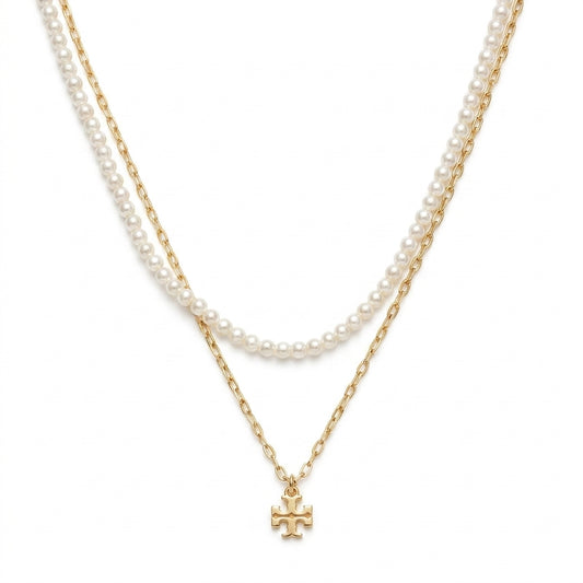 A double-strand necklace featuring a strand of white pearls and a gold chain with a small gold cross pendant, displayed against a solid white background.
