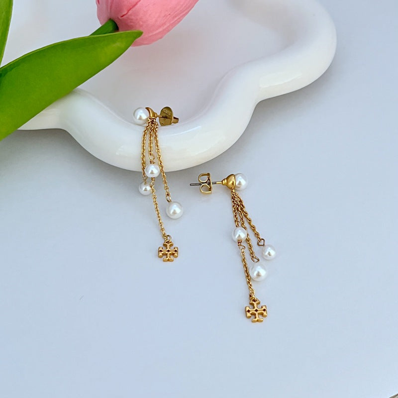  Clean, vertical-oriented shot of a single earring against a plain background, showcasing the elongated bar design, clear logo, and pearl drop in one elegant line.