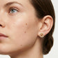 Close-up of a woman wearing gold earrings with a neutral background
