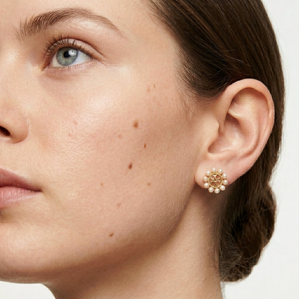 Close-up of a woman wearing gold earrings with a neutral background