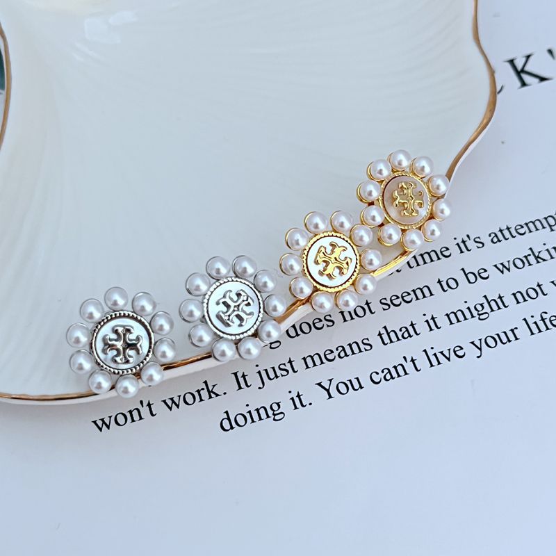 Both studs displayed face-up on a soft, light background (ivory or pale green), highlighting the floral shape and central pearl.