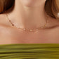 The necklace worn with a crisp white button-down shirt or simple black top, showing how the two charms rest elegantly near the collarbone.