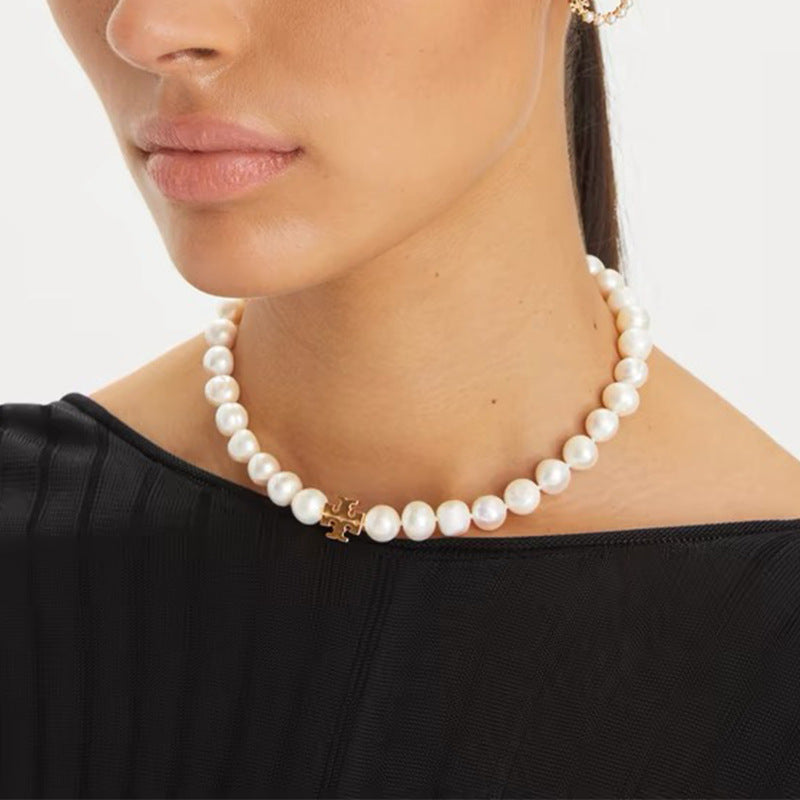 The necklace worn with a crisp white shirt or cashmere sweater, capturing its versatile elegance in a daytime setting.