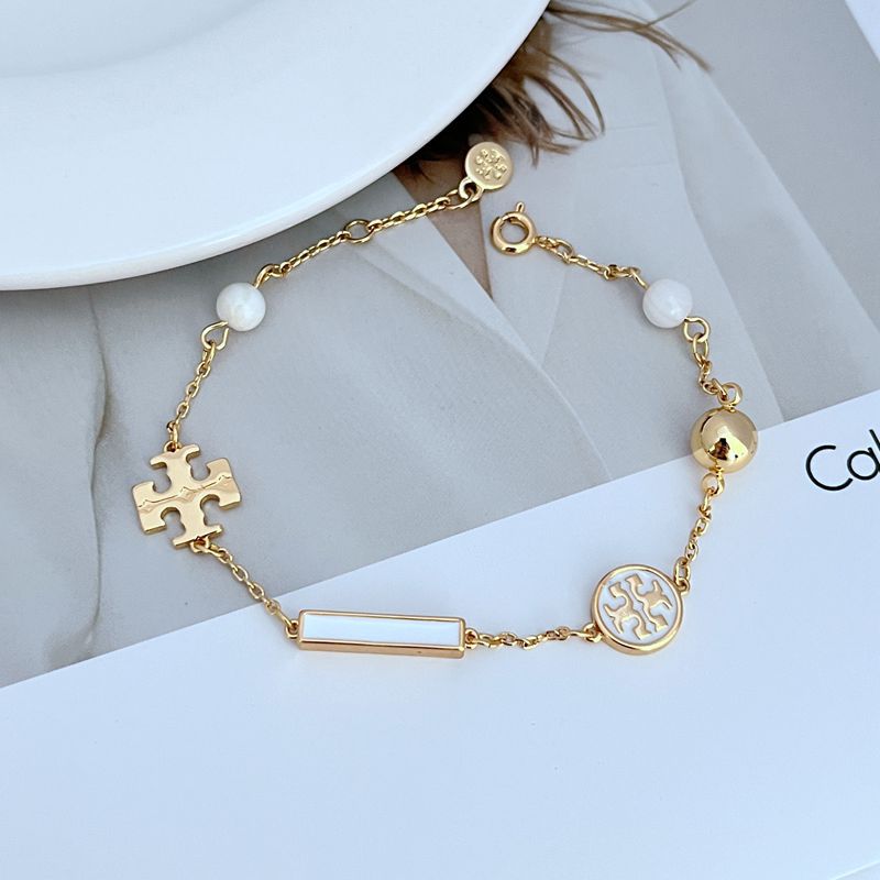 Bracelet laid in a naturally scattered, curved shape on a textured neutral background, highlighting the asymmetric placement of beads and charms.