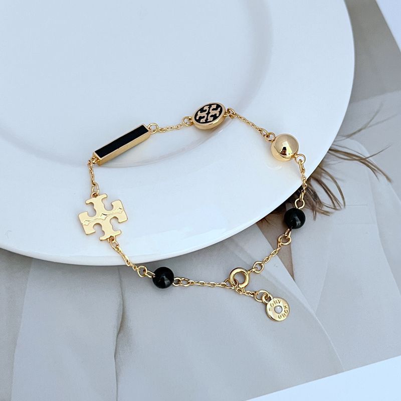 Bracelet laid in a naturally scattered, curved shape on a textured neutral background, highlighting the asymmetric placement of beads and charms.
